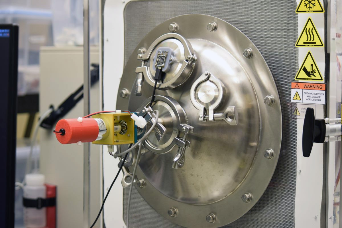 A domed stainless steel panel with electronic devices on it, mounted to the door of a freeze-drying cabinet