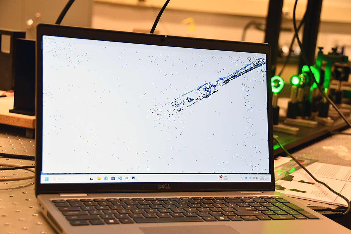 A computer laptop open and showing a sparse array of pixels on a white background