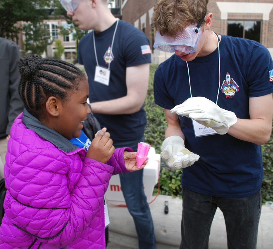 A Purdue student helps a Purdue Space Day participant with her rocket experiment