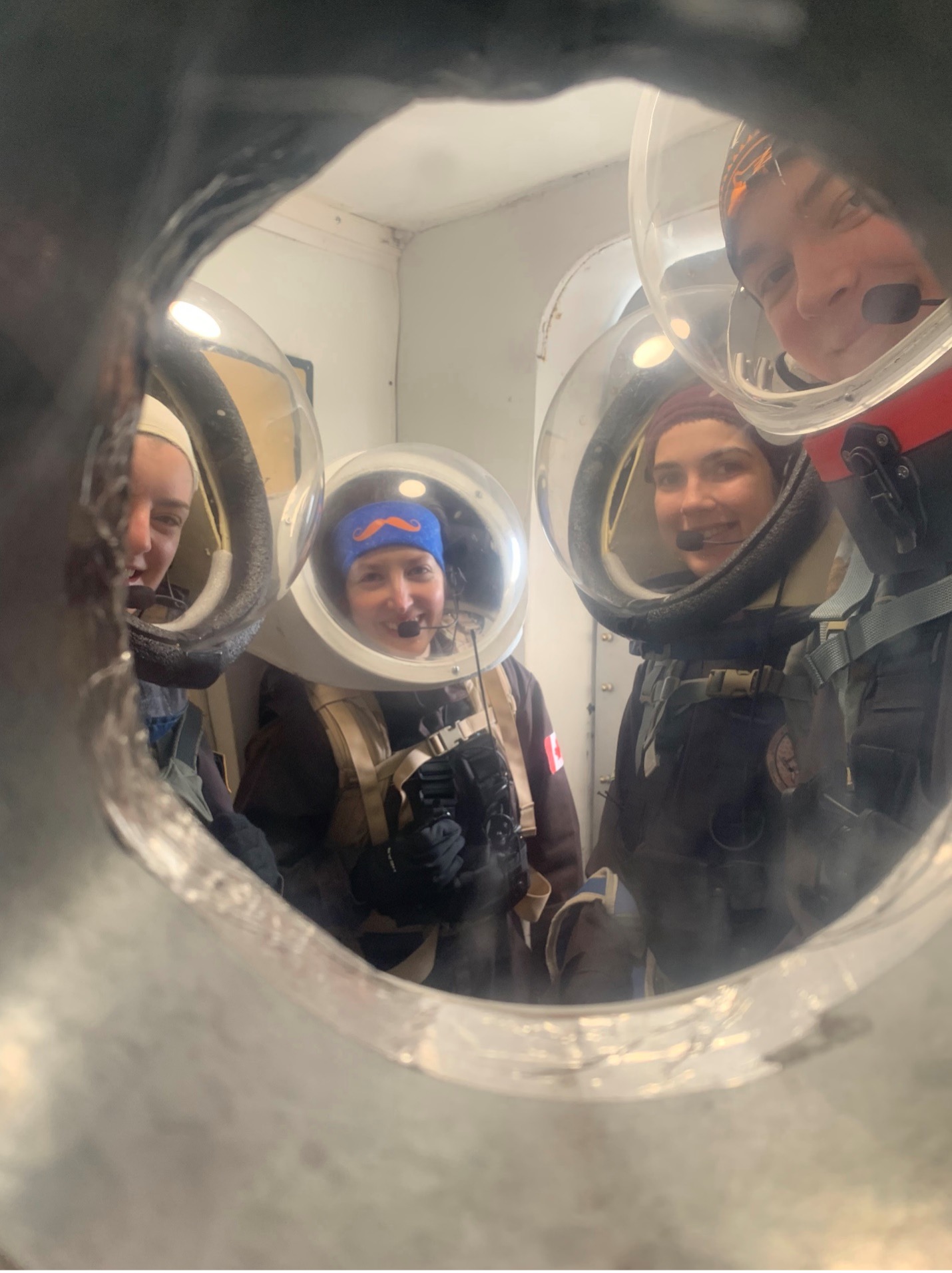 four students in space suits in an airlock