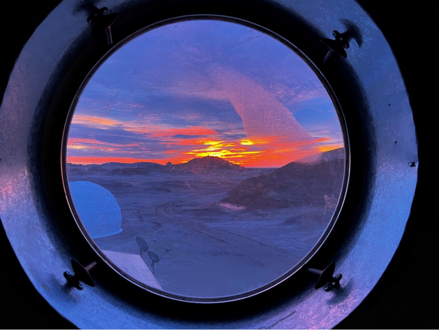 sunrise over the desert as seen through a small round window