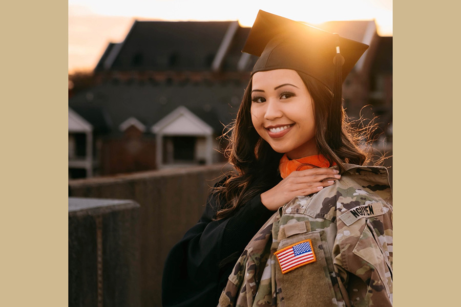 Ellen Nguyen wearing a graduation gown and holding her Army uniform