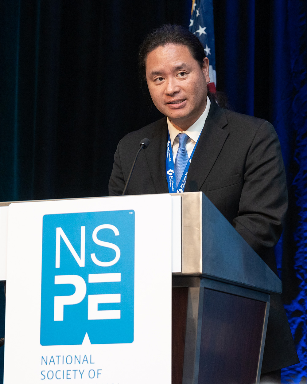 Waterloo Tsutsui speaking from a podium at NSPECon 2023