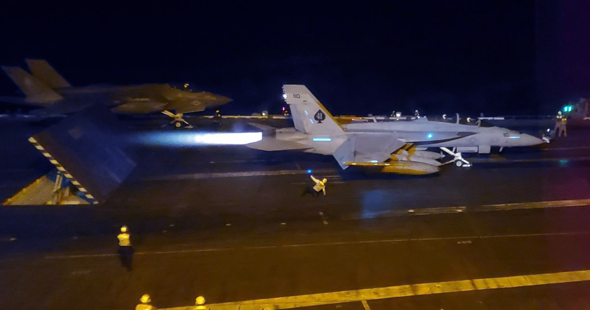 Navy fighter jet on afterburners preparing for a catapult takeoff from an aircraft carrier