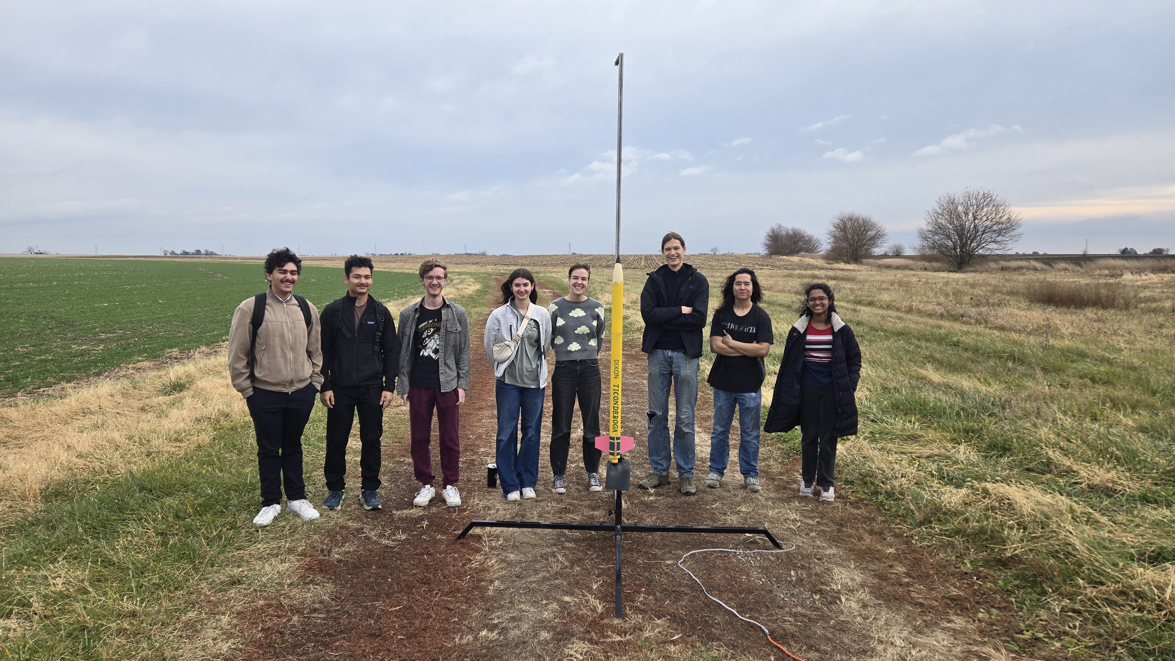 One student team poses with their Ticonderoga pencil-inspired rocket before putting their design and predictions to the test on launch day.