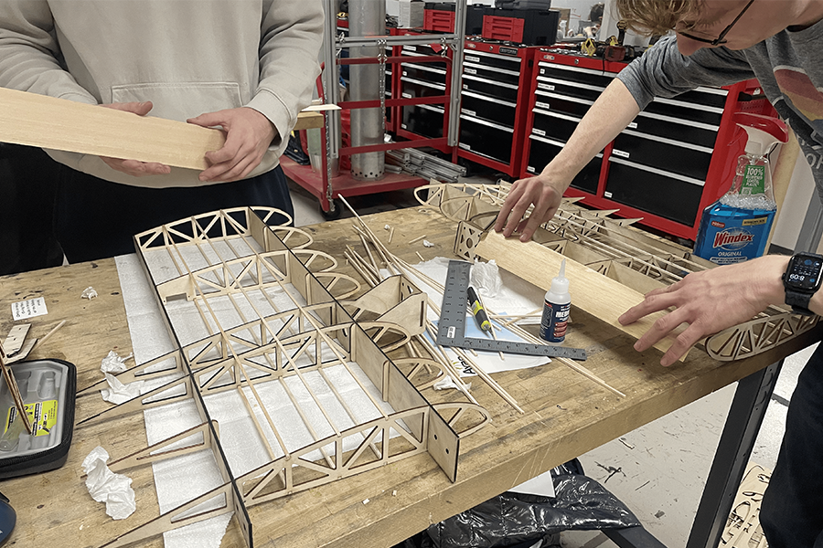 Wood framing of wings being assembled by two students