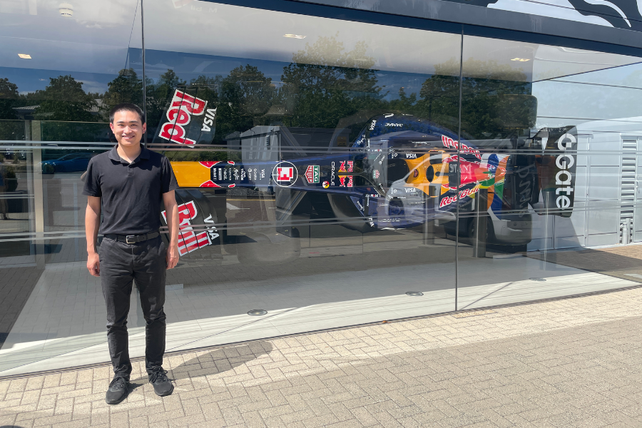 Chenkai Zhang stands outside Red Bull Racing alongside one of the team's Formula 1 cars.