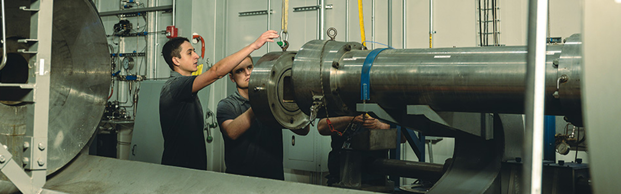 Two students moving a large steel tube section into position.