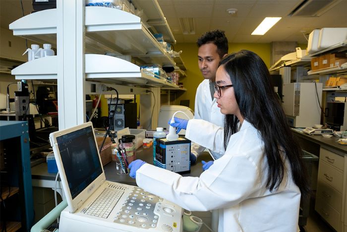 Two people in a lab with lab coats on.
