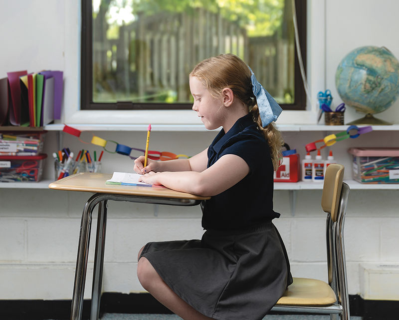 girl sitting at desk in classroom