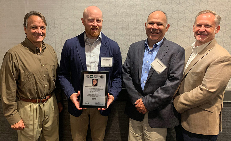 Matthew Hebdon, Ph.D., P.E., holds the plaque recognizing him as the winner of the 2019 Robert J. Dexter Memorial Award Lecture. From left to right: Tom Macioce, P.E., AASHTO T-14 Structural Steel Committee; Matthew Hebdon; Ronald D. Medlock, P.E., High Steel Structures; and Robert J. Connor, Ph.D., Purdue University. Photo by AISI.