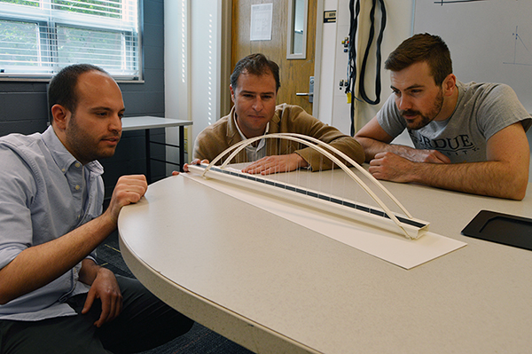 Edward M. Curtis Visiting Professor Luis B. Fargier-Gabaldon (center), Lyles School of Civil Engineering Masters student Dimos Vogdanos (left), and PhD student Will Pollalis review one of the bridges built in the Sizing bridges class.