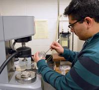 Lyles School undergraduate student Daniel Espinoza places a sample of the laponite gel onto the rheometer. A rheometer measures the way in which a sample flows in response to applied forces.
