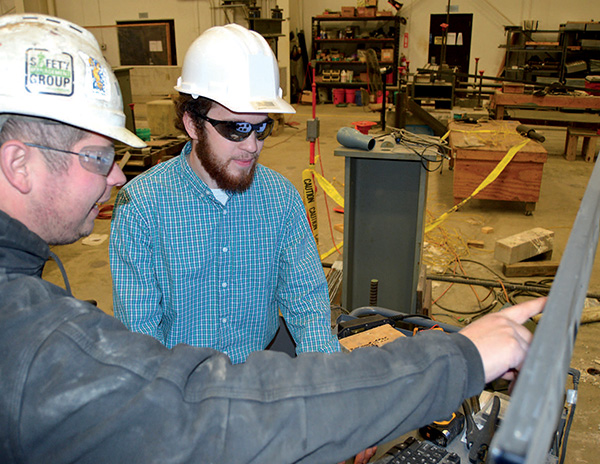Bowen Laboratory project researcher Thomas Bradt and Purdue Civil Engineering undergraduate student Joshua Harmon examine load versus displacement data on web bending of a wide fl ange beam loaded in compression.