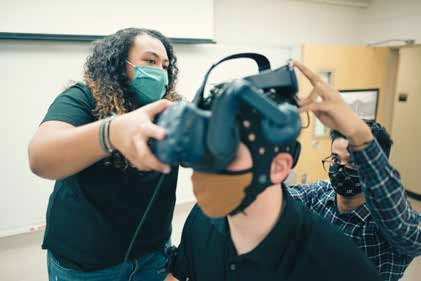 Kaylee Dillard and Aditya Mane place the VR headset on a research subject.