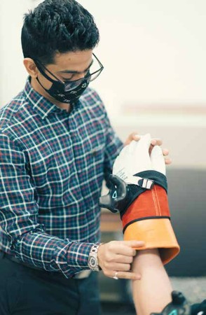 Graduate student Aditya Mane assists a research subject with safety gloves worn by line workers.
