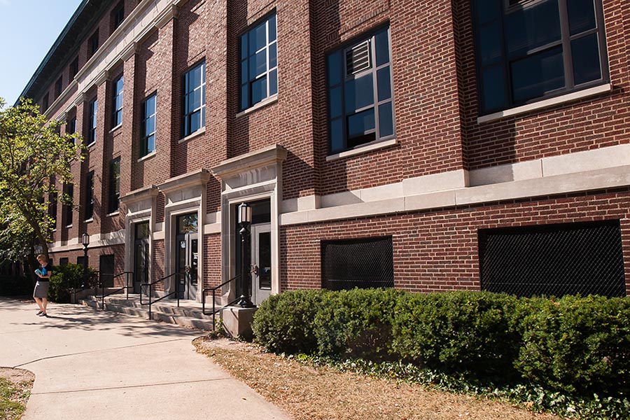 front entrance of the brown hall of electrical engineering on a sunny day, a women walks on the sidewalk