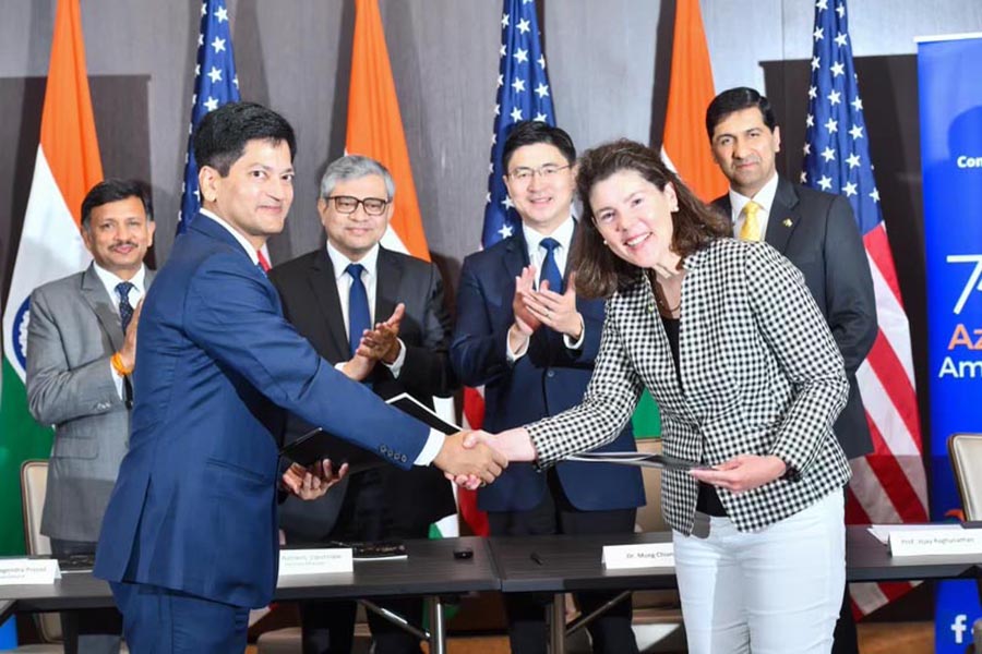 Amitesh Kumar Sinha, CEO of the India Semiconductor Mission and joint secretary in the Indian Ministry of Electronics and IT, and Alyssa Wilcox, senior vice president for partnerships and the presidents chief of staff at Purdue, shake hands. Behind them, standing, are Nagendra Prasad, Consul General of the Indian Consulate in San Francisco; Honorable Ashwini Vaishnaw, India's Union Minister for Railways, Communications, Electronics and IT; Purdue President Mung Chiang; and Vijay Raghunathan, Purdue professor and Associate Head of Electrical and Computer Engineering and Director of Semiconductor Education for Purdue. They are stiting at a table and looking proudl.