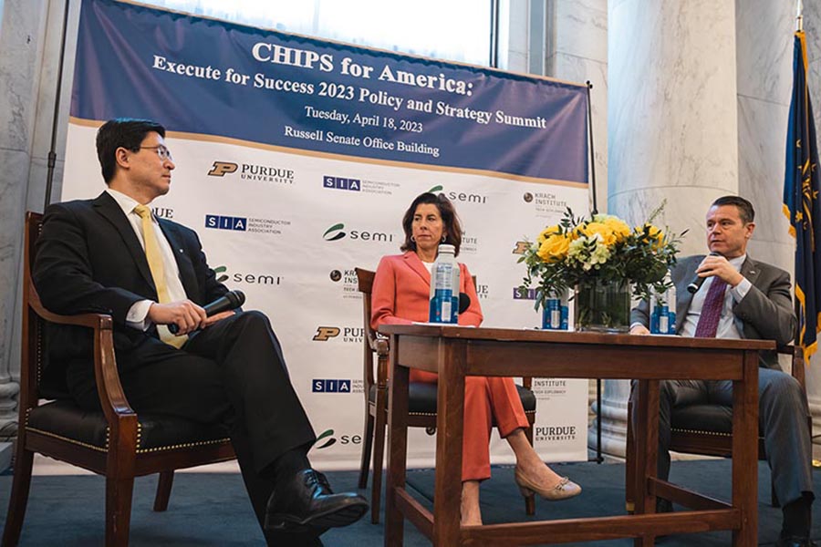 Purdue University President Mung Chiang sits on a stage with US Commerce Secretary Gina Raimondo and US Senator Todd Young