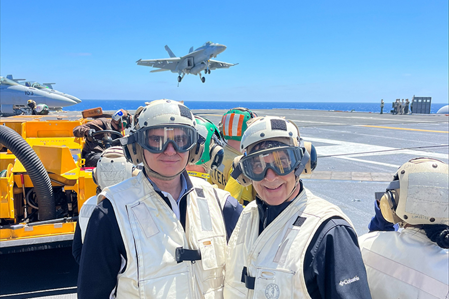 Frank Dooley and Dimitri Peroulis are wearing safety gear while on the flight deck of the USS Nimitz.