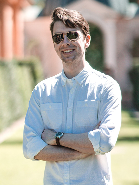 Portrait of David Nickel. He is wearing a blue button up shirt and aviator sunglasses.