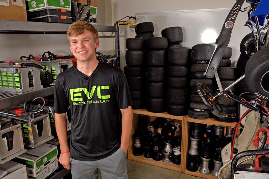 Club president Matthew Kane stands in a storage room full of batteries, car parts, and tires for Purdue Electric Vehicle Club.