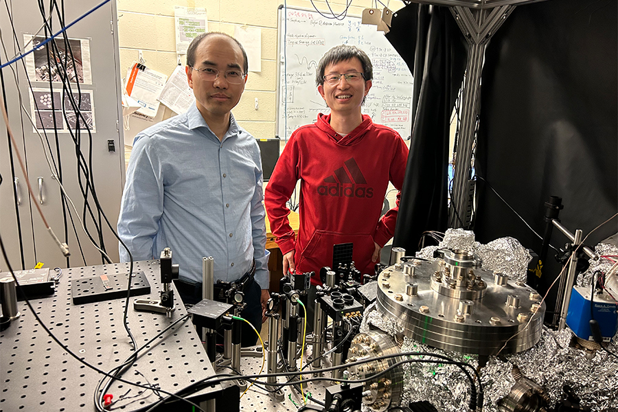 Professor Li and Peng Ju, stand behind lab equipment.