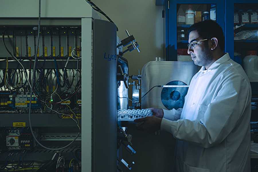 Ahmad Darwish is wearing safety glasses and a labcoat while preparing an experiement.