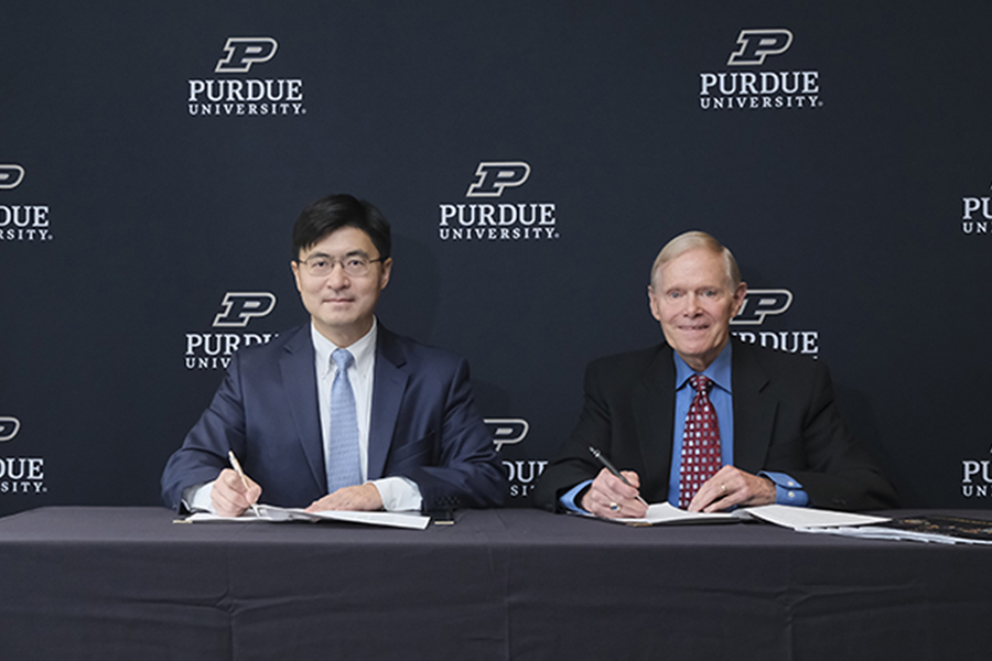 Purdue President Mung Chiang sits to the left of the Rick Cassidy, chairman of TSMC Arizona, in front of  Purdue University backdrop.