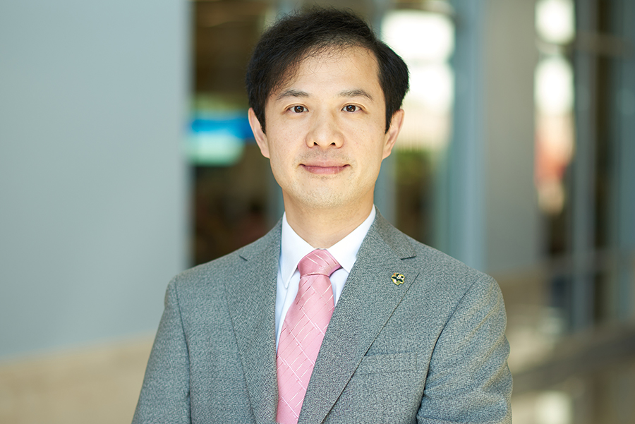 Professor Wang poses for a portrait in the atrium of the MSEE building. He is wearing a gray suit, white shirt, and pink tie.