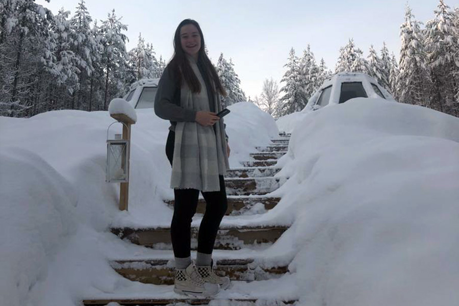 ECE student, Caroline Gilbert, smiles as she stands on a staircase that is surrounded by a large snowfall