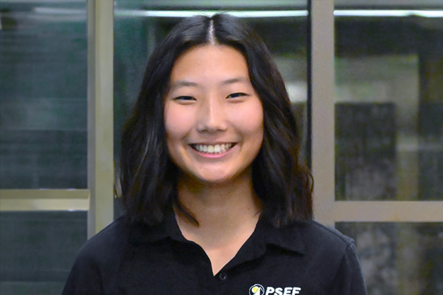 A woman wearing a black shirt smiles warmly, exuding joy and positivity in her expression