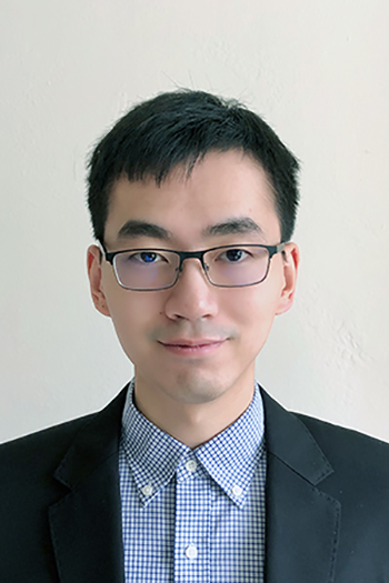Portrait of Professor Junjie Qin. He is wearing a blue shirt, black suit jacket, and glasses.
