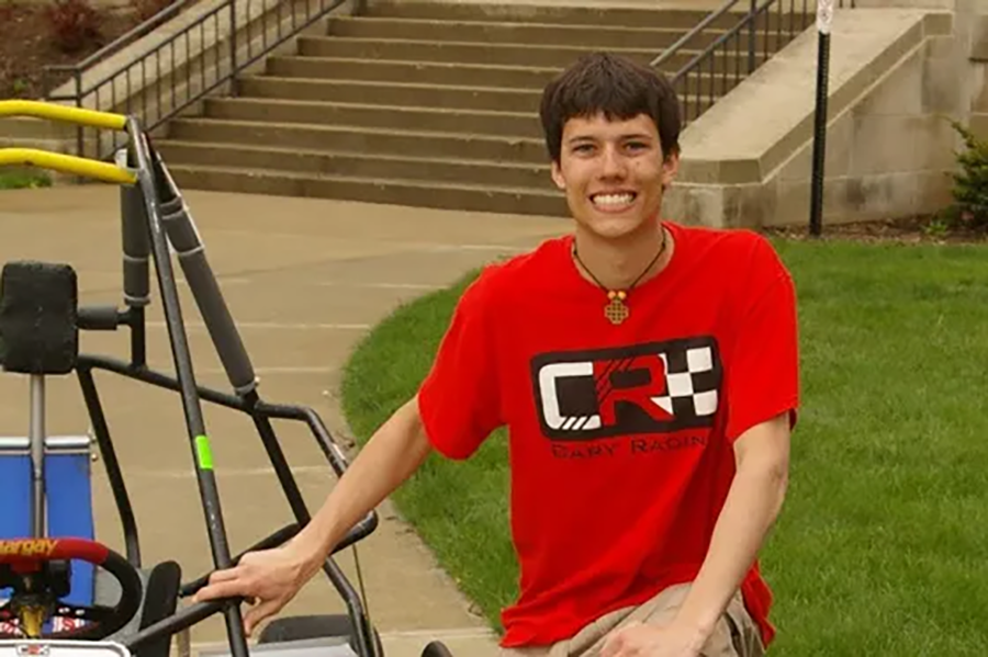 Andrew Boldt, wearing a red Cary Racing t shirt, stands outside Cary Quadrangle with a go kart that races in the Purdue Grand Prix.