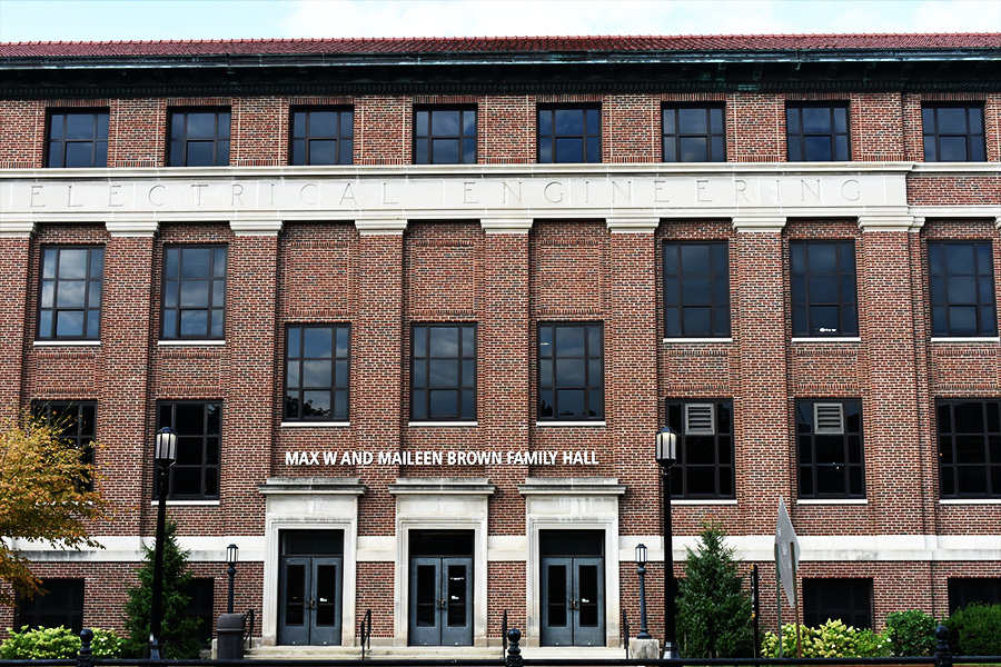 Front view of a red-brick building with "Electrical Engineering" engraved on the facade. Three stories, large black-framed windows, and multiple entrances.