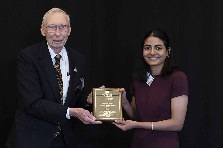 Jim Eaton and Dr. Harshita Singh pose for a picture. They are both holding on to her Dr. Singh's award plaque and are standing in front of a black background.