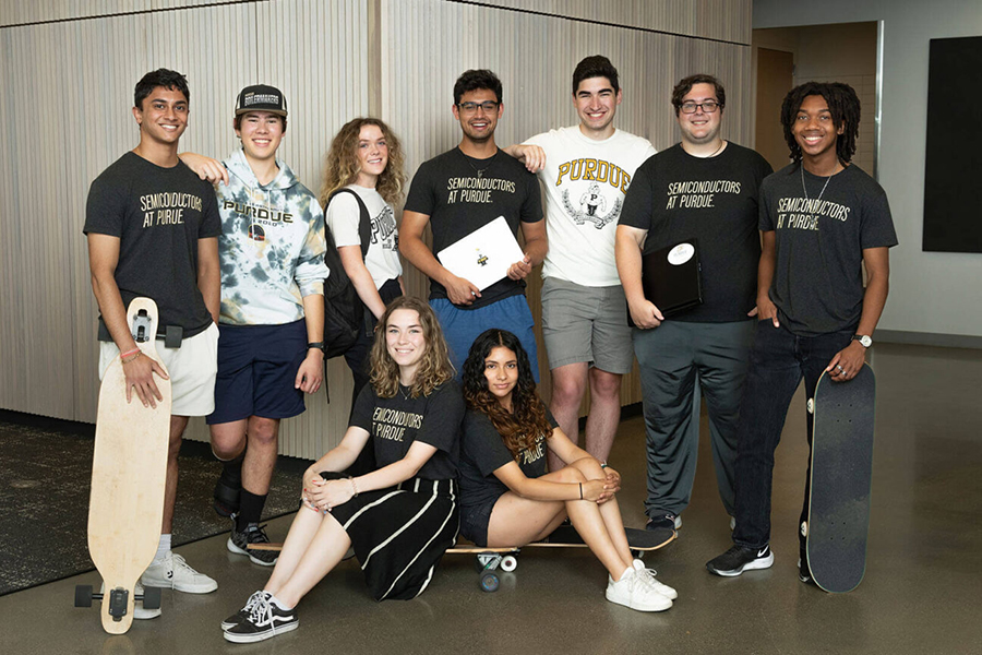 Students in a summer semiconductor program gather for a group photo. They are all wearing Purdue gear while two sit on skateboards.