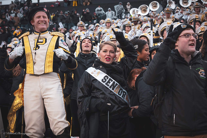 Emma with her senior sash at a Purdue football game, posed in the stands.