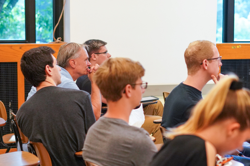 Rick Thomas listens to David Schwind's presentation to students