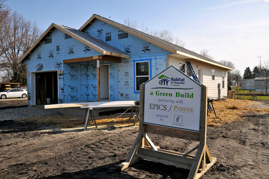 Habitat for Humanity sign with "partnering with EPICS" on it; in front of a house that is being sided