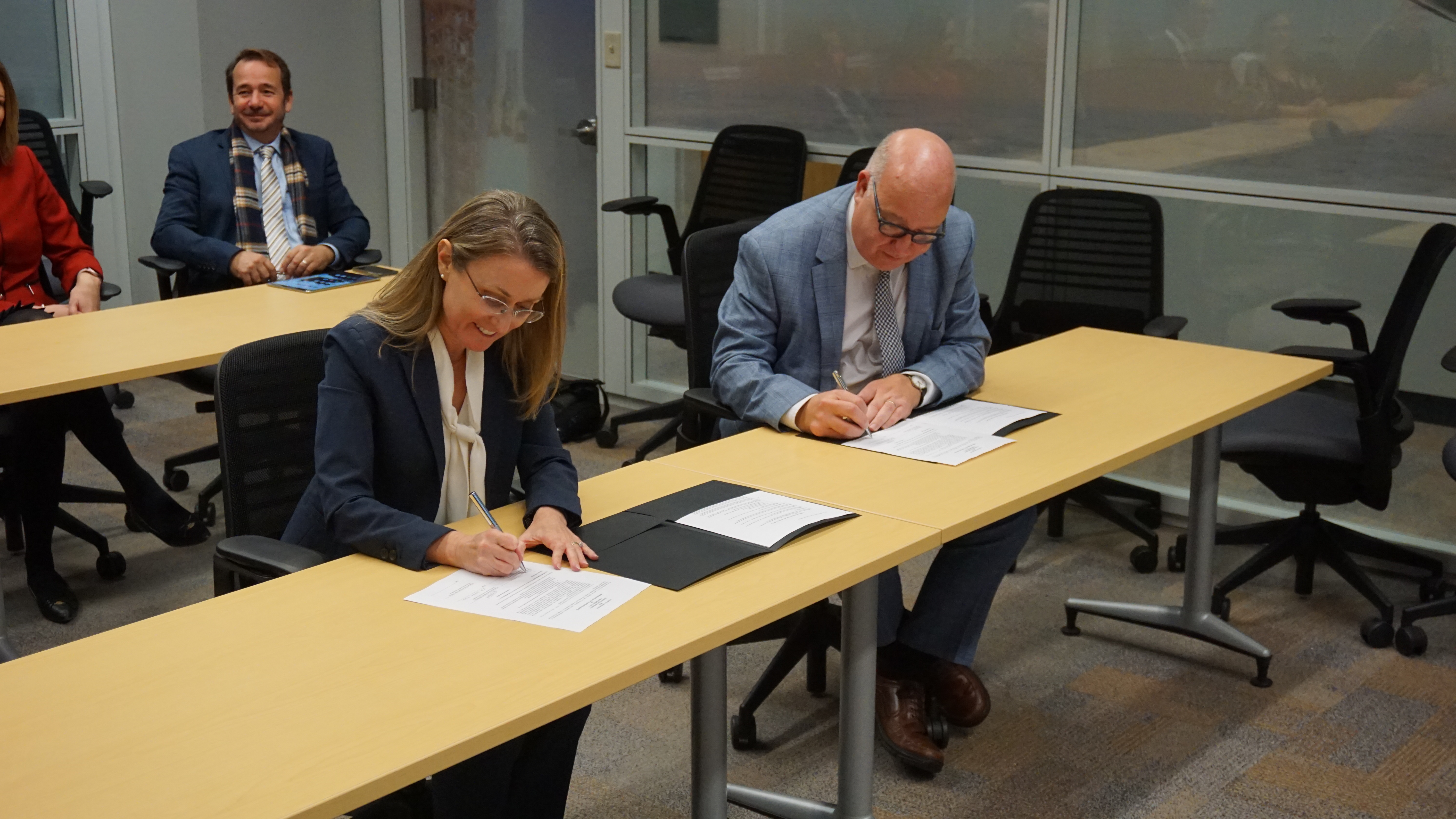 Theresa Mayer, executive vice president for research and partnerships at Purdue, and Simon Pollard, pro-vice-chancellor international at Cranfield University, sign the MOU amendment to expand the defense education and research partnership between Purdue and Cranfield