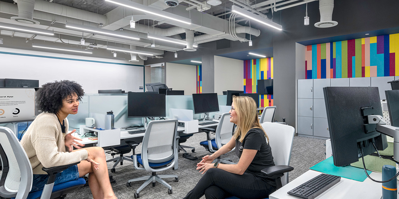 A room with chairs and peiple studying with large glass windows