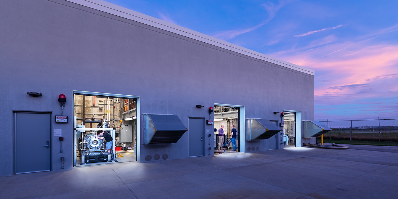 Outside view of a building with garage doors opened, showing individuals working on things