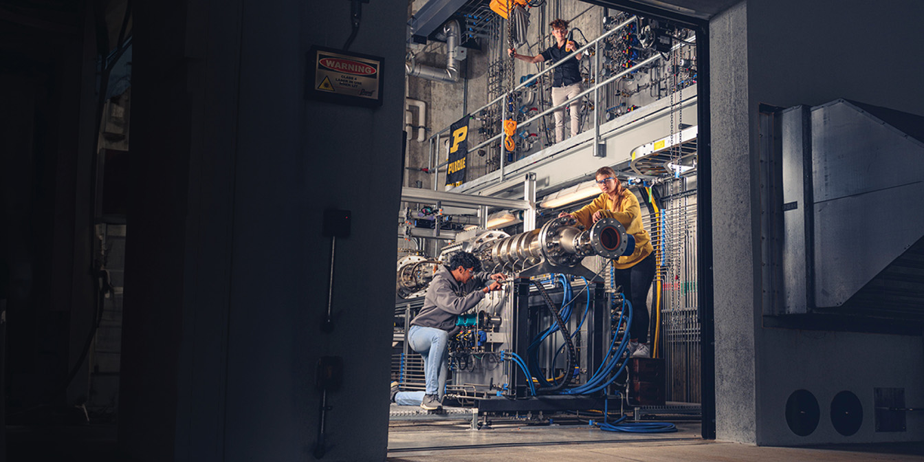 Open garage door with three people working on a machine