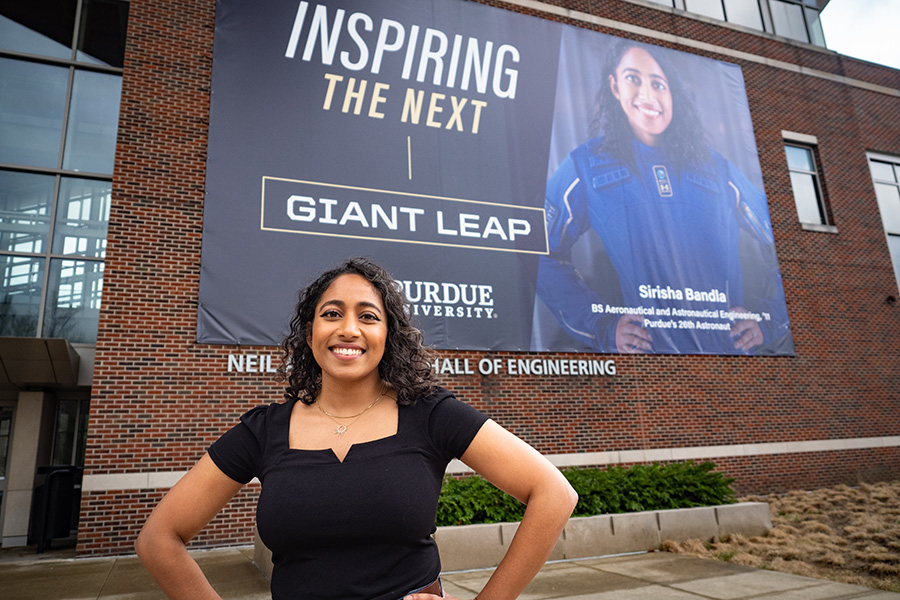 Sirisha Bandla standing in front of her banner in Neil Armstrong Hall of Engineering