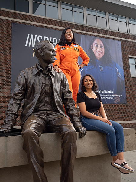 Sirisha Bandla and Thendral Kamal standing next to Neil Armstrong statue