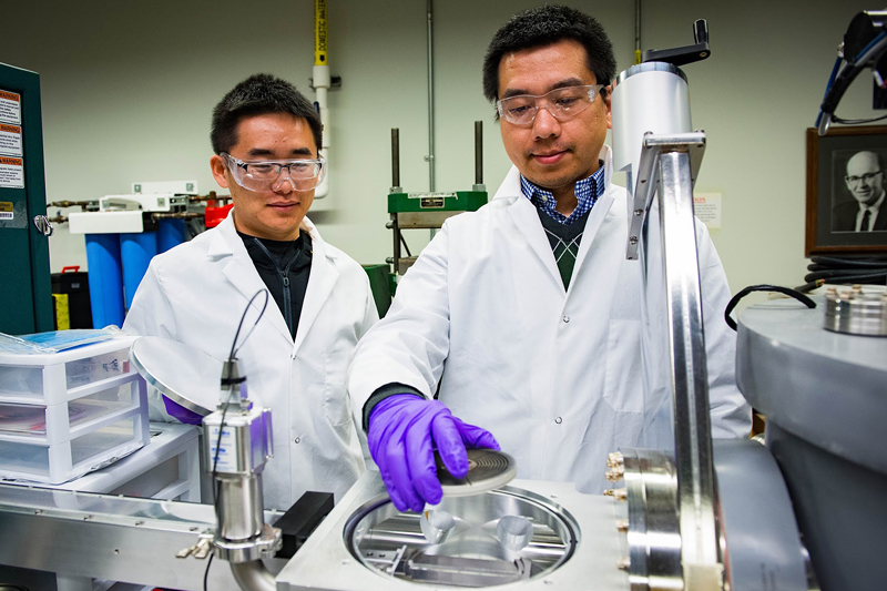 Purdue postdoctoral research associate Sichuang Xue, at left, and doctoral student Qiang Li, prepare a sample for research to create super-strong aluminum alloys.