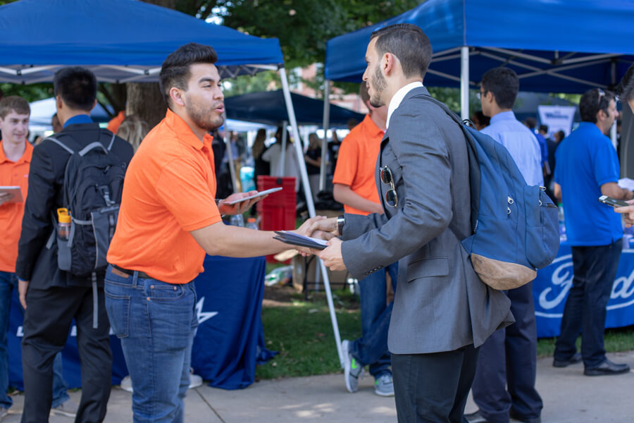 A student shakes hands with a Lockheed-Martin representative.