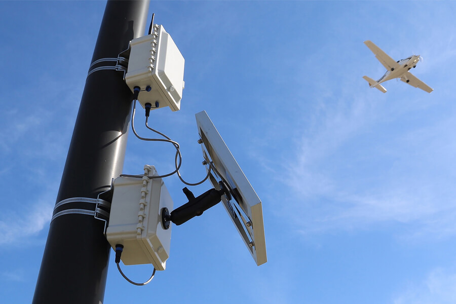A plane flies over the Blueavion f1 data collection technology at the Purdue University Airport. The device uses data collection technology to help small airports improve operations data collection. The technology was developed at Purdue University and is available through Bluemac Analytics.