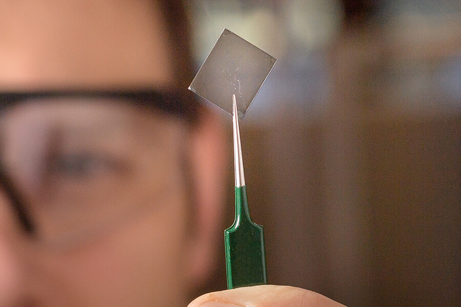 Purdue researcher Brett Savoie holds a transparent polymer film that conducts electricity inexpensively and easily.